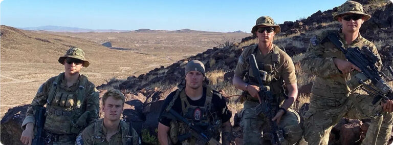 Group of soldiers posing on a rocky desert hill