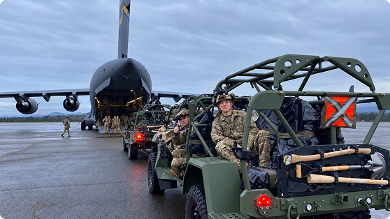 Soldiers in military vehicles next to a cargo plane